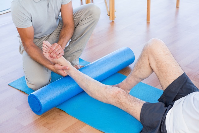 Trainer working with man on exercise mat
