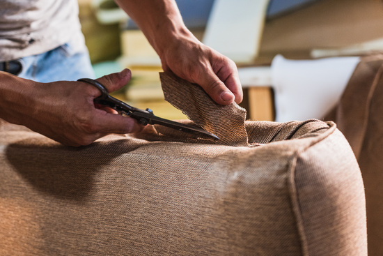 Person cutting fabric from DIY cushion project.