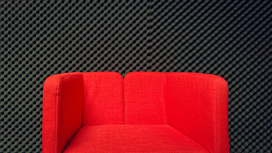 Red chair in front of a wall of egg crate foam