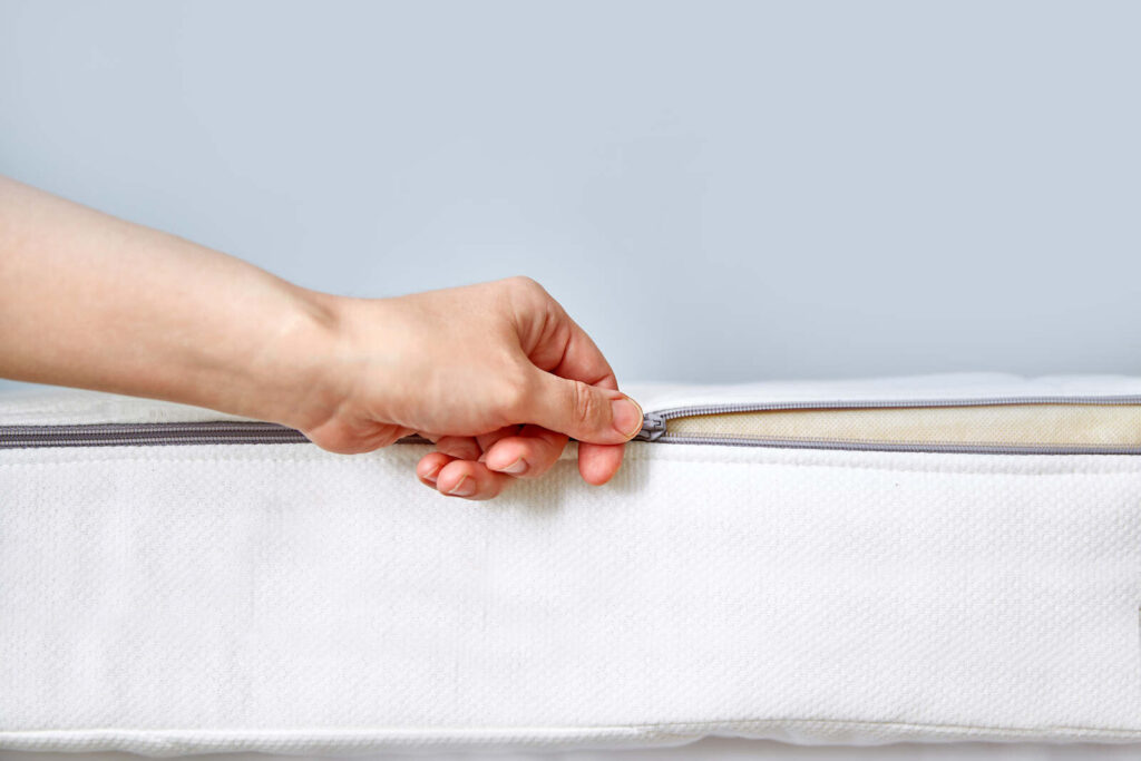 Hand unzipping a foam mattress