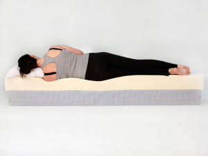 person laying on their side on a mattress