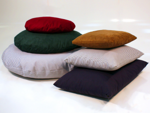 square and round pet beds stacked on top of each other in various colors