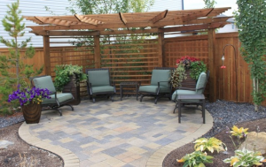 A brick patio with outdoor foam cushion chairs and potted plants, surrounded by other plants and flowers